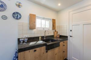 a kitchen with a sink and a window at Welcome in - Vakantiewoning met grote tuin en green egg I Lepelstraat 18c Vrouwenpolder in Vrouwenpolder