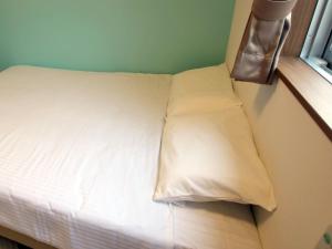ein Bett mit weißer Bettwäsche und Kissen neben einem Fenster in der Unterkunft Rich Lison Ishigaki in Ishigaki-jima