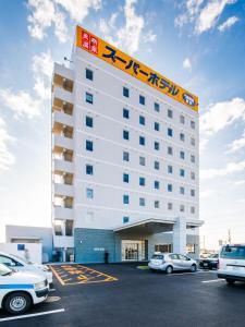a hotel building with cars parked in a parking lot at Super Hotel Kashima in Kamisu