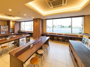 a restaurant with tables and stools and a large window at Super Hotel Kashima in Kamisu