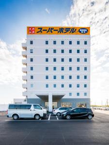 a hotel with cars parked in a parking lot at Super Hotel Kashima in Kamisu