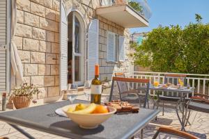 a table with a bowl of fruit and a bottle of wine at Villa Kate Dadić in Dubrovnik