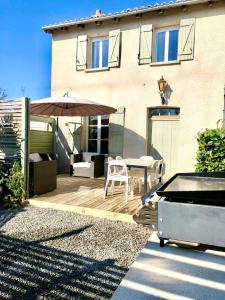 een patio met een parasol en een tafel en stoelen bij Maison Hirondelles Gîtes in Mézières-sur-Issoire