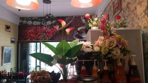 Amaretto & Caffe Hostel في سوراثاني: غرفة بها مجموعة من الزهور والزجاجات