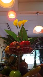 a plate of tomatoes and a plant on a stand at Amaretto & Caffe Hostel in Suratthani