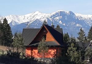 a cabin with snow covered mountains in the background at Cyrwony Domek in Poronin