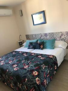 um quarto com uma cama com um cobertor e almofadas em Vivienda Vacacional Casa Federico em Corralejo