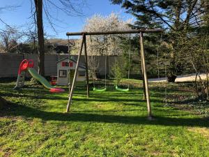 um parque infantil com um baloiço num quintal em Le charme d'othe em Bellechaume