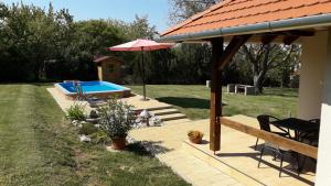 a wooden deck with a pool and an umbrella at Cseresznyevirág Vendégházak in Kővágószőlős