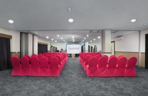 una sala de conferencias con sillas rojas y una pantalla en favehotel Malang, en Malang