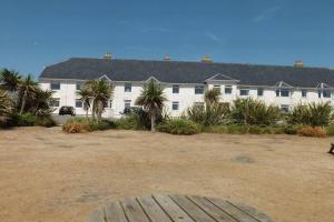 a large white building with palm trees in front of it at PLAS DARIEN-3 BED APT- SEA VIEWS - SLEEPS 5 in Trearddur