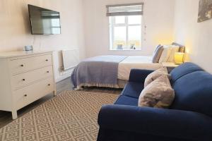 a bedroom with a bed and a blue couch at PLAS DARIEN-3 BED APT- SEA VIEWS - SLEEPS 5 in Trearddur