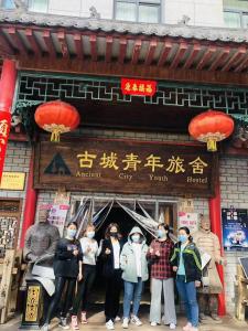 un grupo de personas usando máscaras delante de un edificio en Ancient City International Youth Hostel, en Xi'an