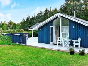 a blue shed with a table and chairs in a yard at Peaceful Holiday Home in L kken 500 M from the Ocean in Lønstrup