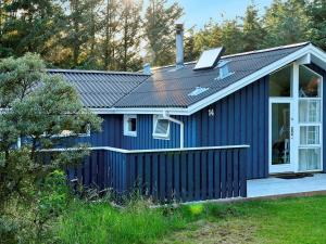 a blue tiny house with a porch at Peaceful Holiday Home in L kken 500 M from the Ocean in Lønstrup
