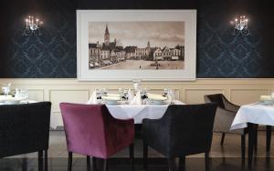 a dining room with a table with chairs and a picture at Hotel Olesno in Olesno