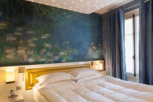 パリにあるプティ マドレーヌ ホテルの絵画の前に大きなベッドが備わるベッドルーム