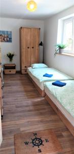 two beds in a room with wooden floors at EKO - Domek jezioro Steszewko in Stęszewko