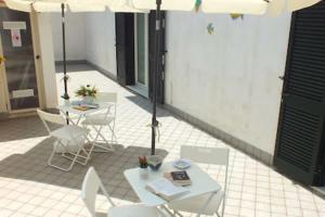 un patio con sedie e tavoli bianchi e ombrellone di Bacidapompei a Scafati