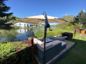 eine Terrasse mit einem Regenschirm neben einem Fluss in der Unterkunft SEA Office - Modernes Ferienhaus mit tollem Seeblick in Kirchheim