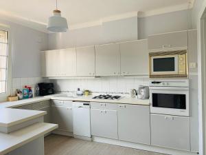 a white kitchen with white cabinets and a microwave at Harmonie Tergnier in Tergnier