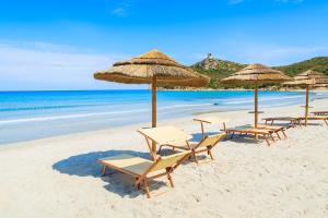 un gruppo di sedie e ombrelloni in spiaggia di Maya Holiday Home a Villasimius