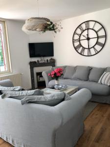 uma sala de estar com um sofá e um relógio na parede em Along The River em Bergerac