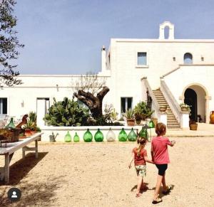 deux enfants jouant avec un frisbee devant une maison dans l'établissement Masseria Fulcignano, à Galatone