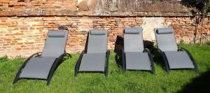 vier Stühle im Gras neben einer Ziegelmauer in der Unterkunft Auberge des chemins in Moissac