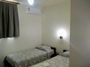 a small room with two beds and a window at Colina Park Hotel in Piracicaba