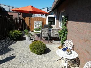 eine Terrasse mit einem Tisch, Stühlen und einem Sonnenschirm in der Unterkunft Feriendomizil Familie Finke in Weener