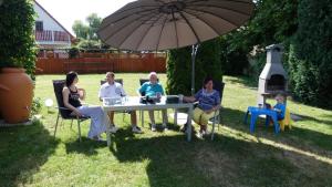 a group of women sitting around a table under an umbrella at FeWo an der Havel in Zehdenick