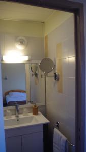 a bathroom with a sink and a mirror and a bed at Le Robinson in Pierrelatte