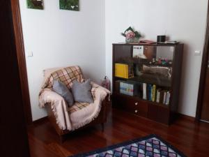sala de estar con silla y estante para libros en Casa da Prainha, en São Caetano