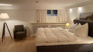 ein großes weißes Bett in einem Zimmer mit Stuhl in der Unterkunft Sylthaus in Archsum