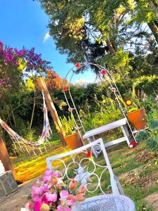 biała ławka siedząca w ogrodzie z kwiatami w obiekcie Chalé pinheiro velho w mieście Monte Verde