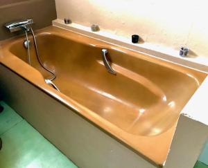 La salle de bains est pourvue d'une baignoire en cuivre avec un robinet. dans l'établissement Logements Un Coin de Bigorre - T2 de campagne - Canal plus & Netflix - Wifi fibre - Centre village, à Tournay