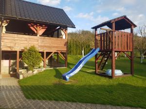 a playground with a slide in the grass next to a building at Apartmány u tenisového kurtu in Mosty u Jablunkova