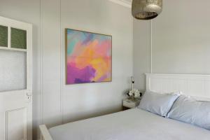 Un dormitorio con una cama blanca y una pintura en la pared en Calm Waters Waterfront Cottages en Sussex inlet