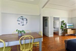 Un comedor con mesa y sillas de madera. en Calm Waters Waterfront Cottages, en Sussex Inlet