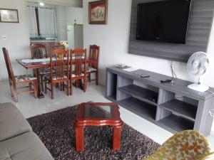 a living room with a television and a table and chairs at Serra Gaúcha Uva e Vinho in Bento Gonçalves