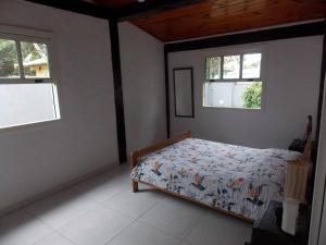 ein Schlafzimmer mit einem Bett in einem Zimmer mit zwei Fenstern in der Unterkunft Búzios Casa de Família - Bosque de Geribá in Búzios