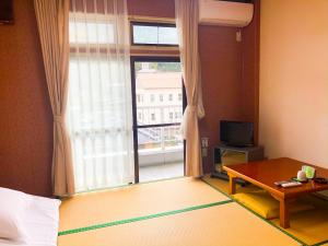 a room with a window and a bed and a table at 宇和パークホテル in Seiyo