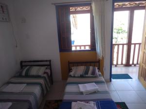 twee bedden in een kamer met twee ramen bij Flores de Búzios Suítes in Búzios