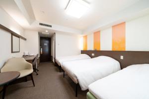 a room with four beds and a desk and a table at Hotel Sunlite Shinjuku in Tokyo