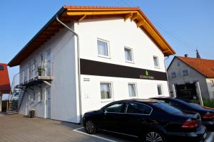 a black car parked in front of a white building at Business Homes - Das Apartment Hotel in Lauchheim