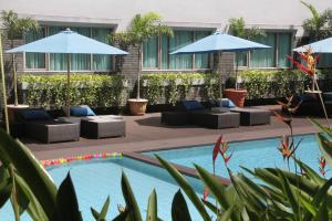 a pool with couches and umbrellas next to a building at ASTON Tropicana Hotel Bandung in Bandung