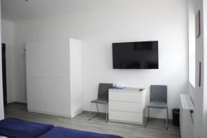 Habitación con 2 sillas, escritorio y TV. en CityPension-Vreden, en Vreden