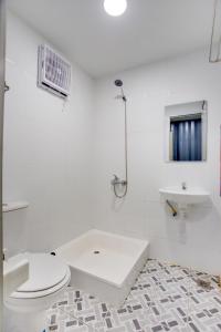 een witte badkamer met een toilet en een wastafel bij Capital O 3300 Nadjara Residence Syariah in Jakarta