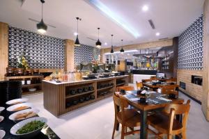 a restaurant with tables and chairs and a kitchen at Neo Dipatiukur Bandung by ASTON in Bandung